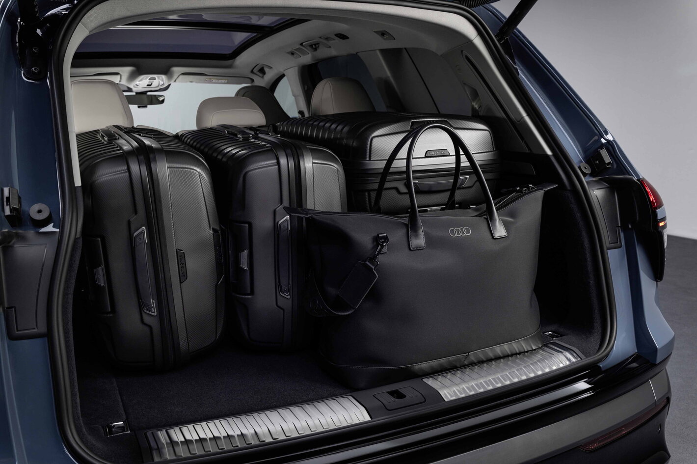 De ruime Audi Q7 kofferbak is gevuld met diverse zwarte reiskoffers en tassen.