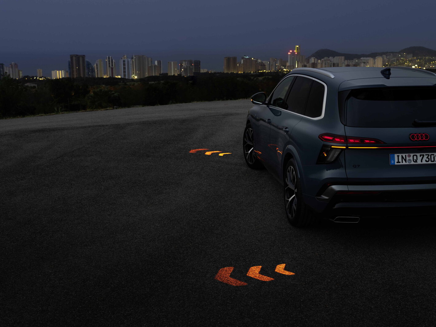 Audi Q7 projecteert dynamische pijlvormige lichten op de grond 's nachts.