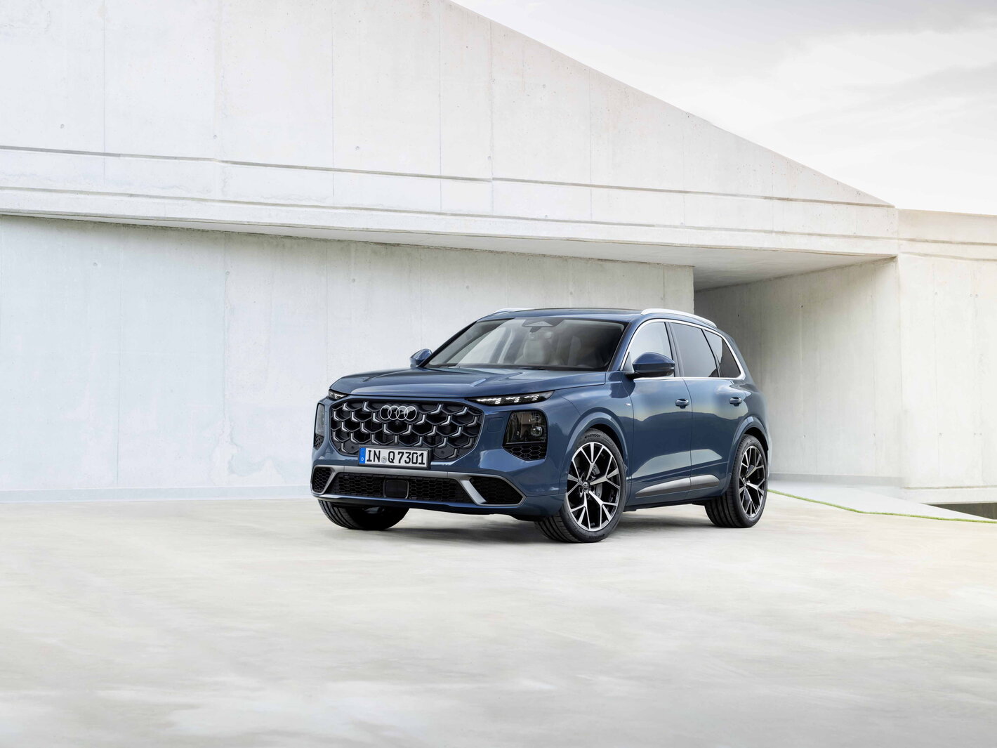 Stijlvolle petrolblauwe Audi Q7, voorkant en zijkant, pronkt met opvallende grille en koplampen.
