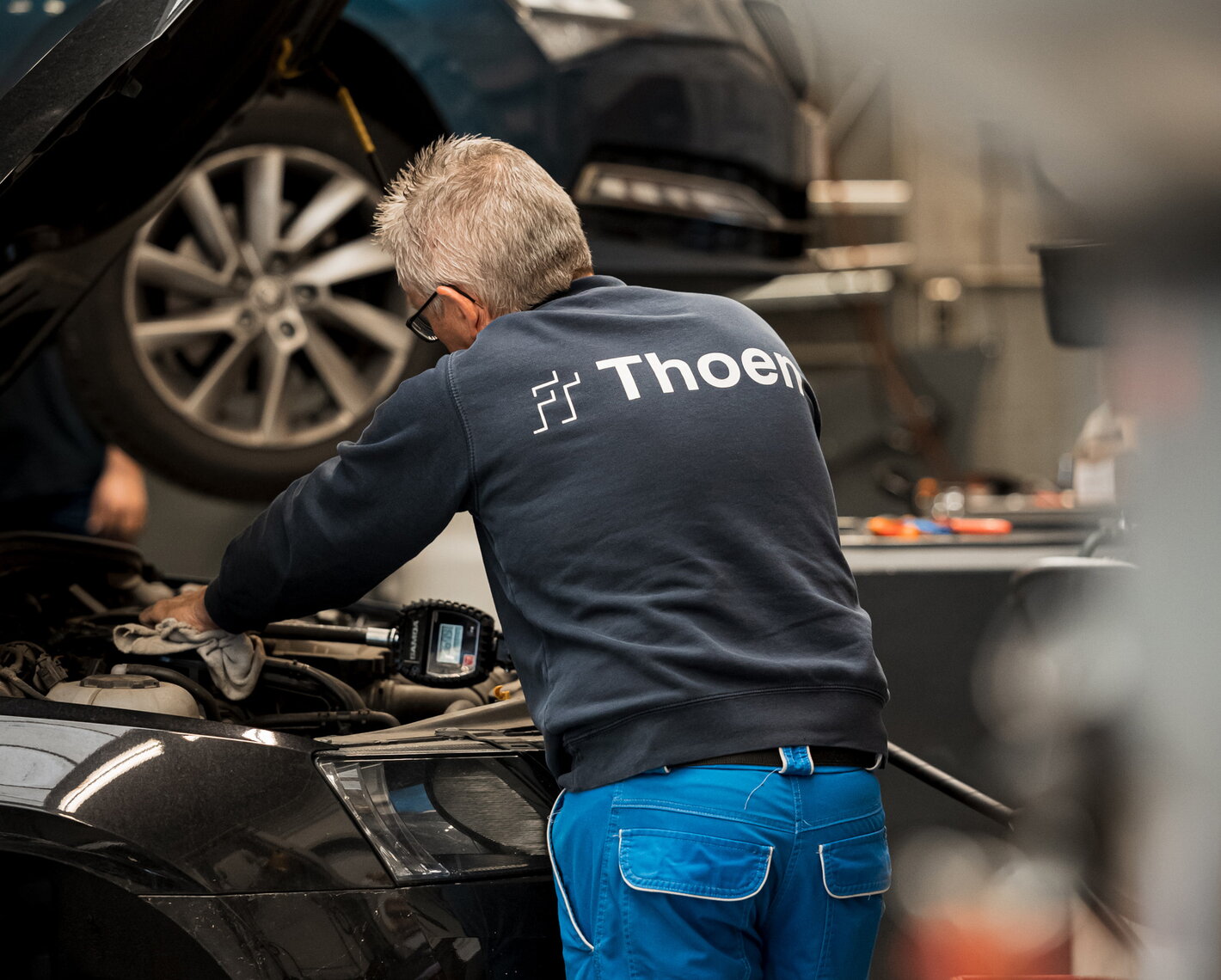 Groep Thoen autotechnieker werkt aan een wagen met gespecialiseerde tools
